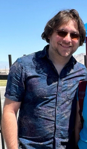 Joe DeLong outdoors, wearing sunglasses and a patterned shirt.