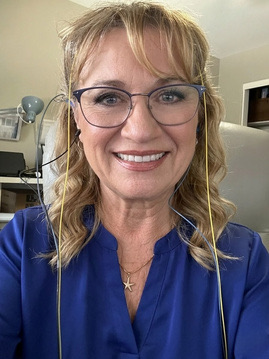 Dr. Lis&eacute; D. DeLong, wearing neurofeedback sensors, smiling at the camera.